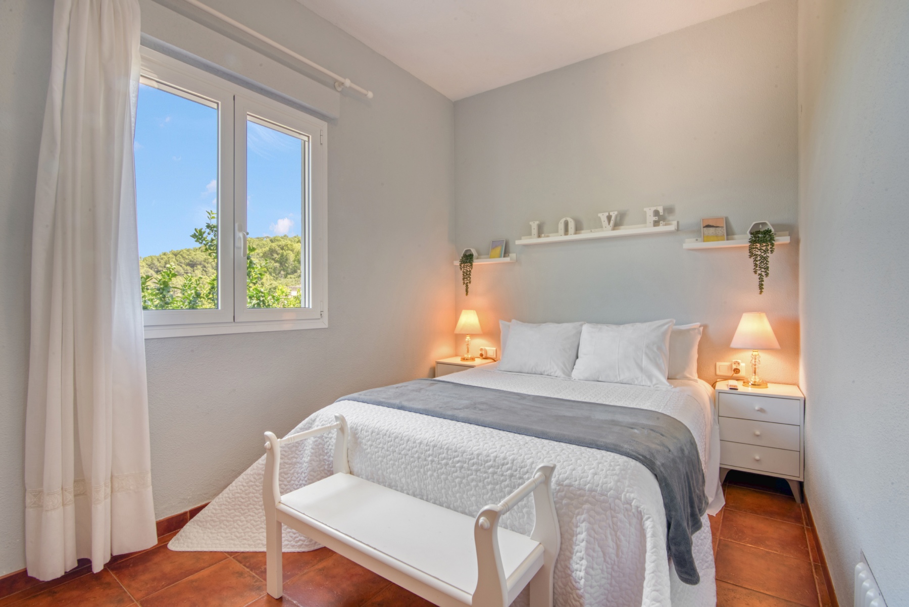 Habitación principal con cama de matrimonio en la planta baja, aire acondicionado, armario abierto, ventilador de techo regulable, juegos de mantas y entrada de aire de la estufa de pellets